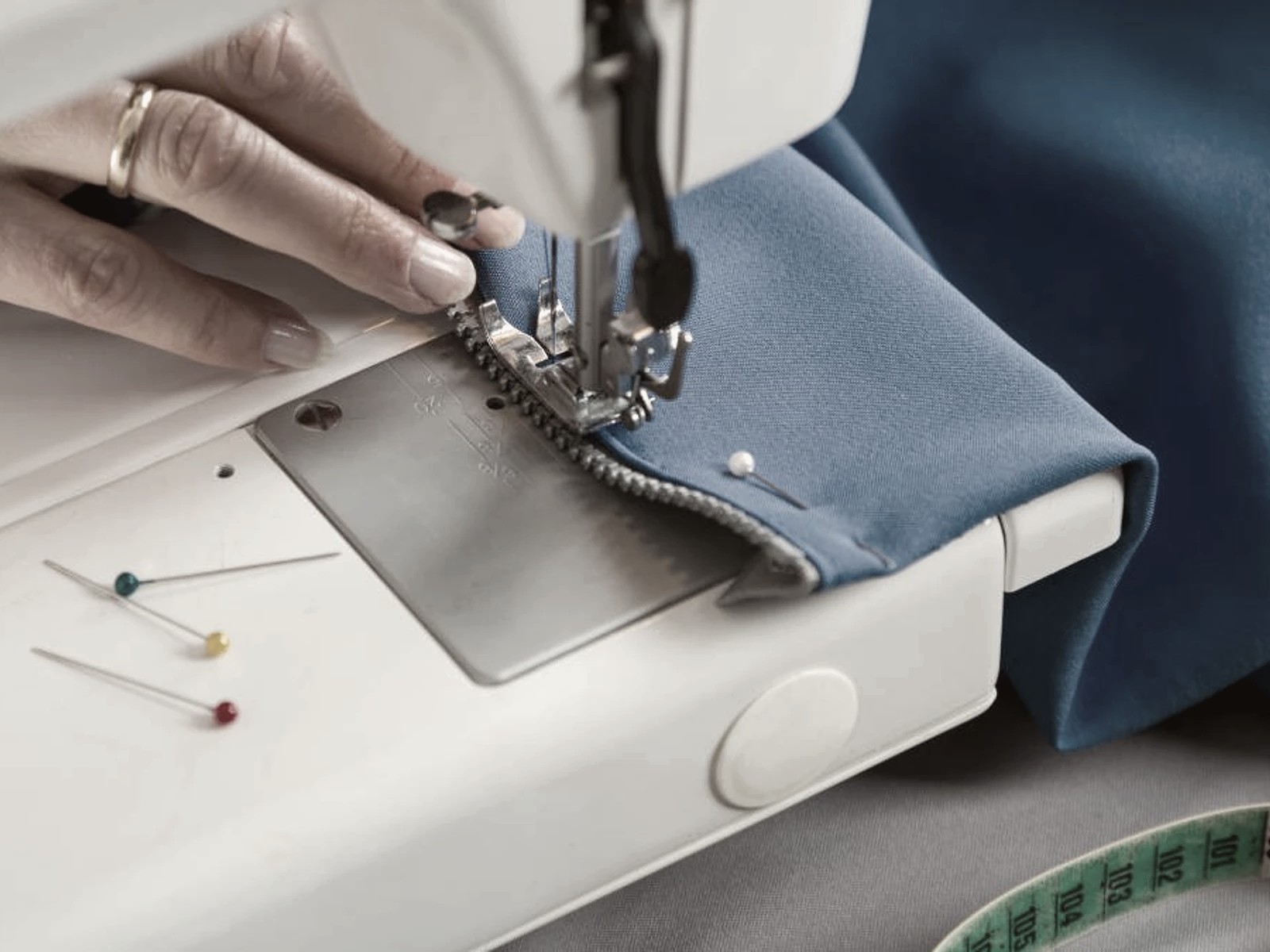 Close-up of a zipper being sewn into a blue garment during alterations at Thread Works Studios