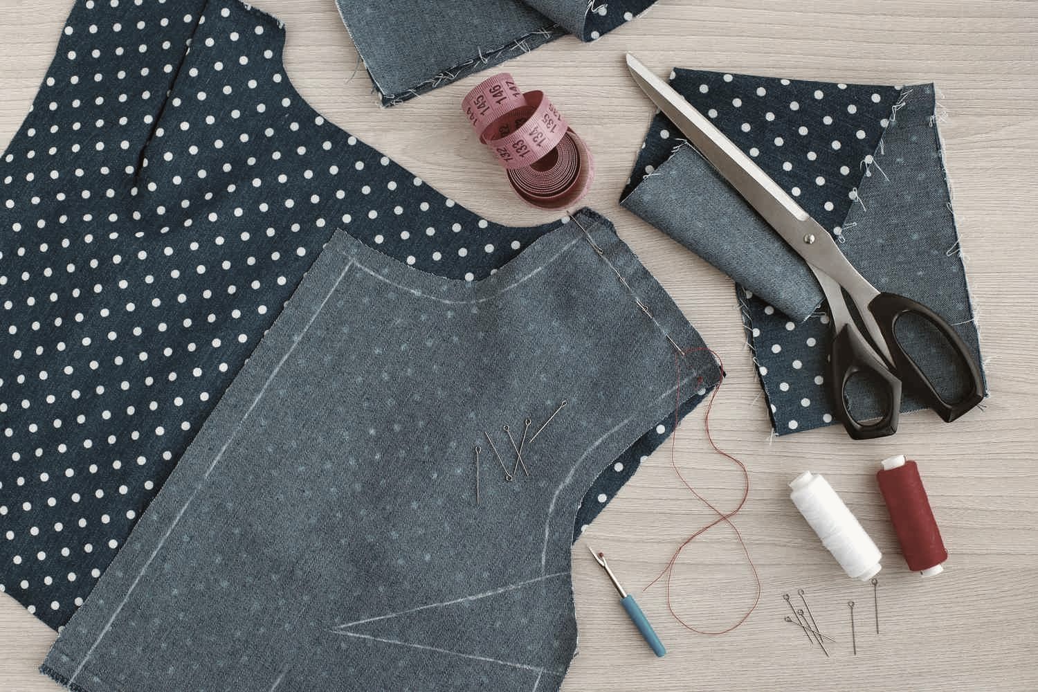 Polka-dot denim garment pieces laid out with pins, thread, and scissors during custom sewing at Thread Works Studios